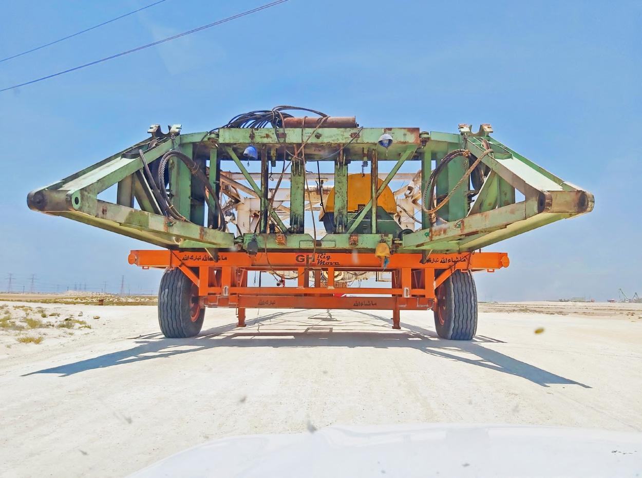 Orange GH Rig Move derrick dolly carrying a green derrick section