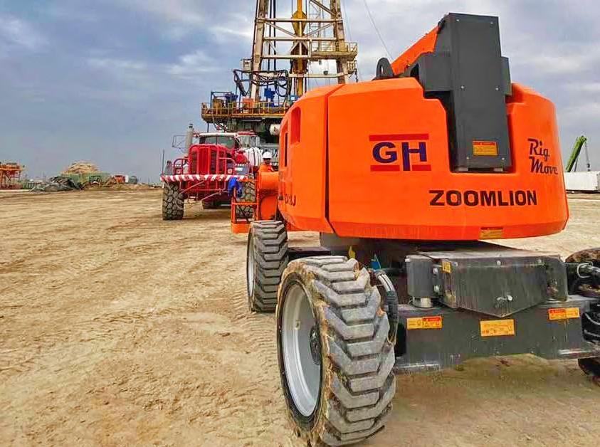 Orange GH Rig Move man lift on site with a rig in the background